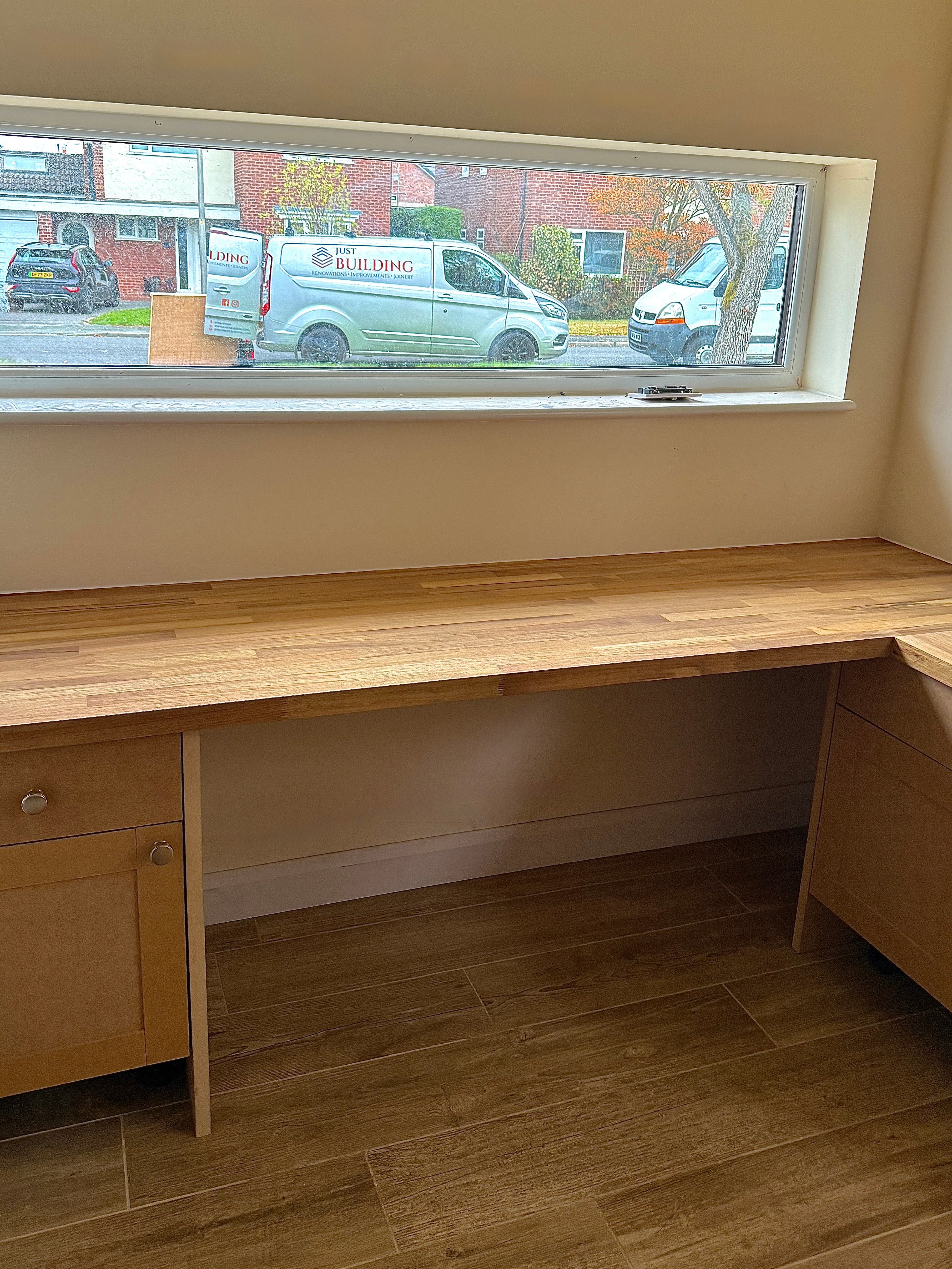 Built-in oak worktop desk with drawer storage below a window