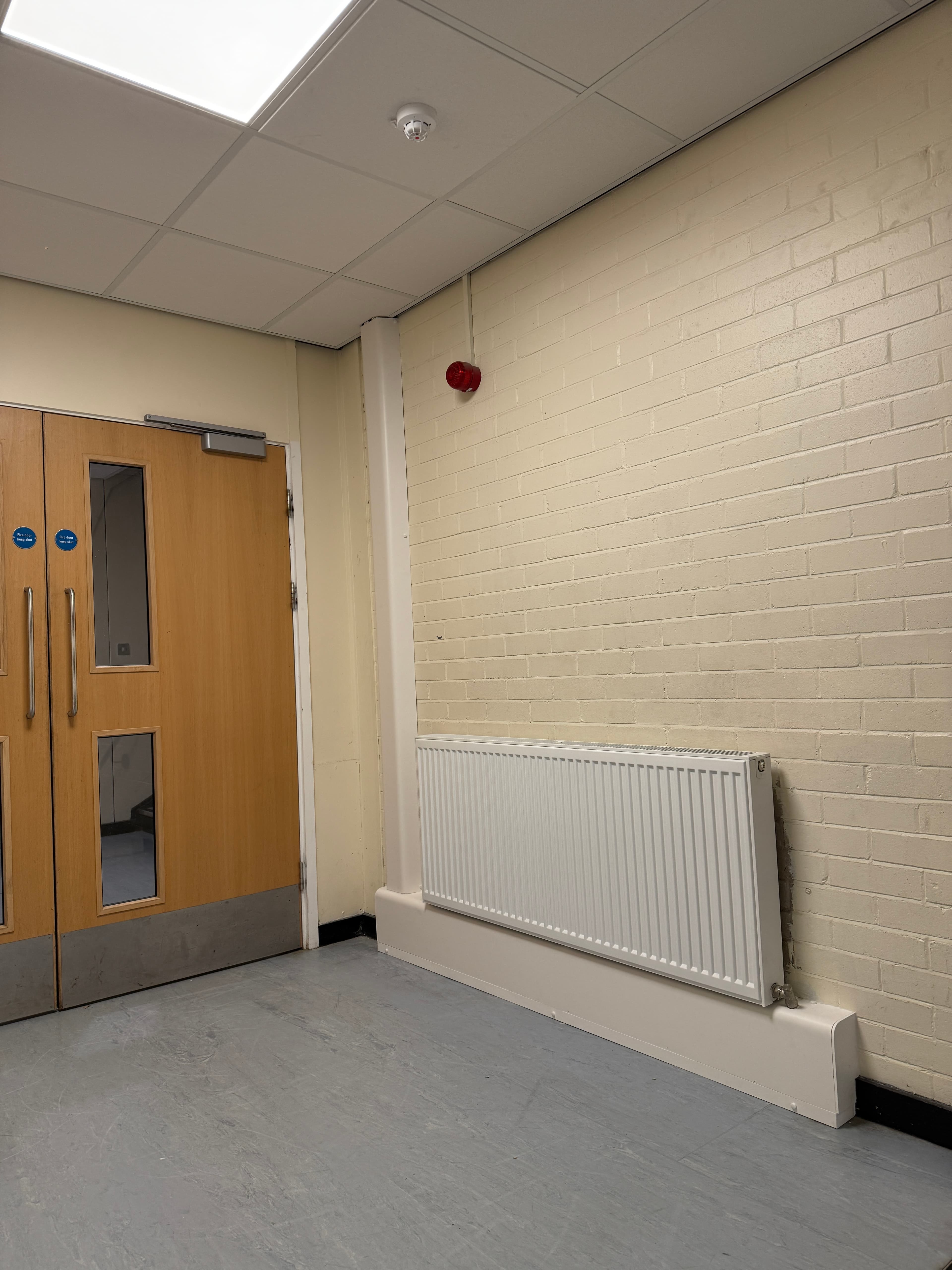 Commercial pipe encasement detail below a corridor radiator