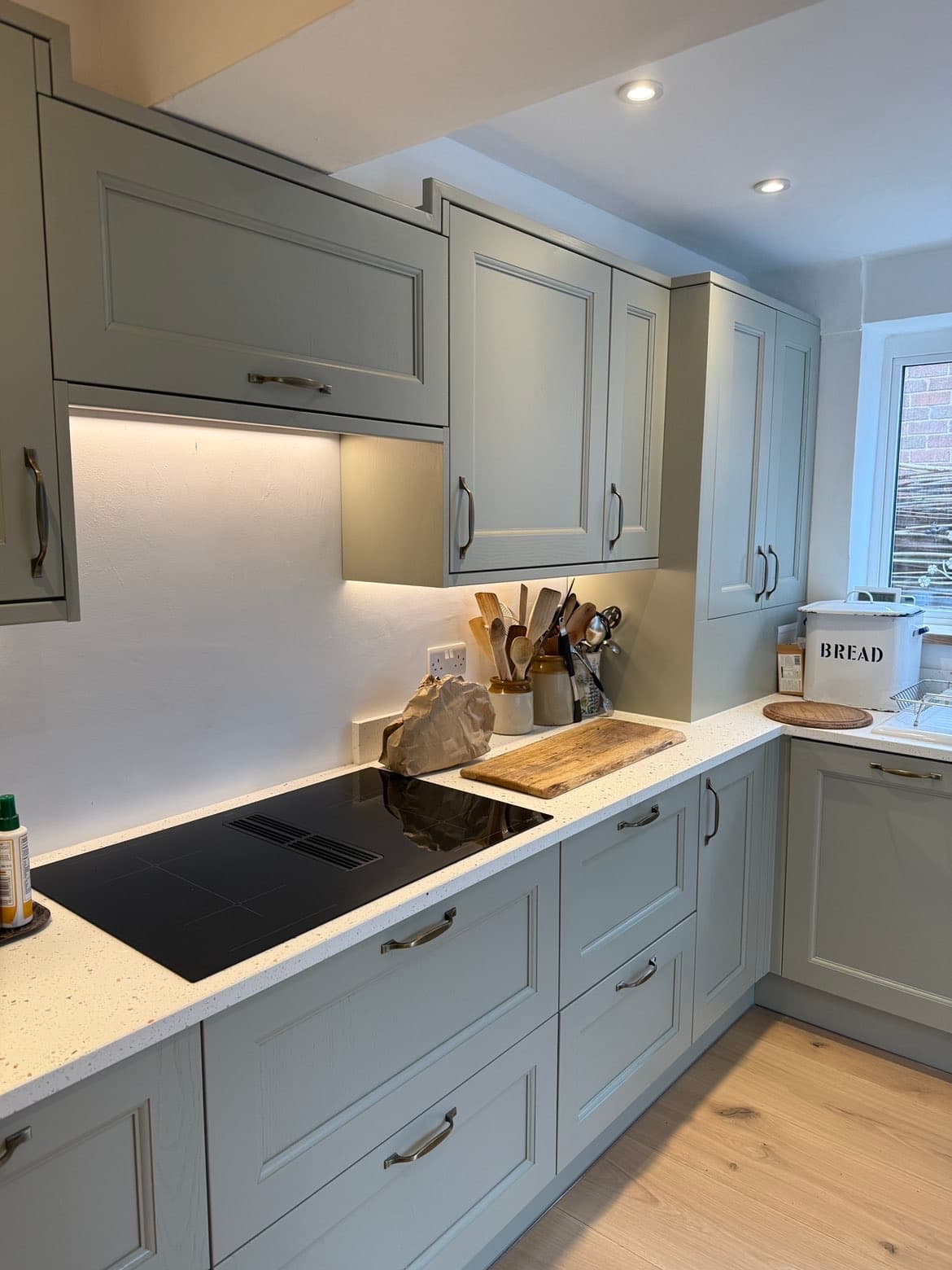 Finished sage green kitchen hob, worktop and wall cabinet detail