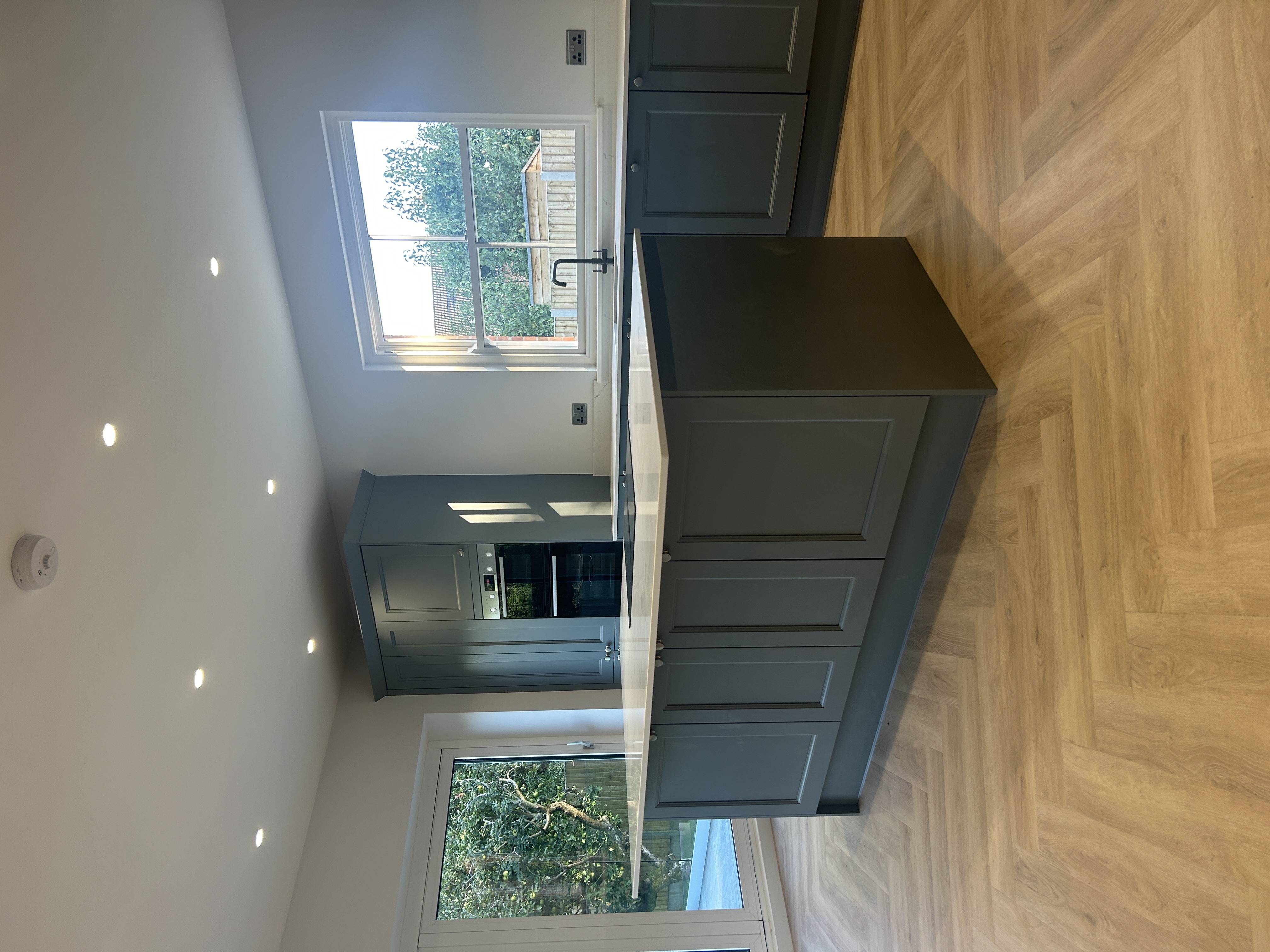 Kitchen island and tall grey shaker units in a finished renovation
