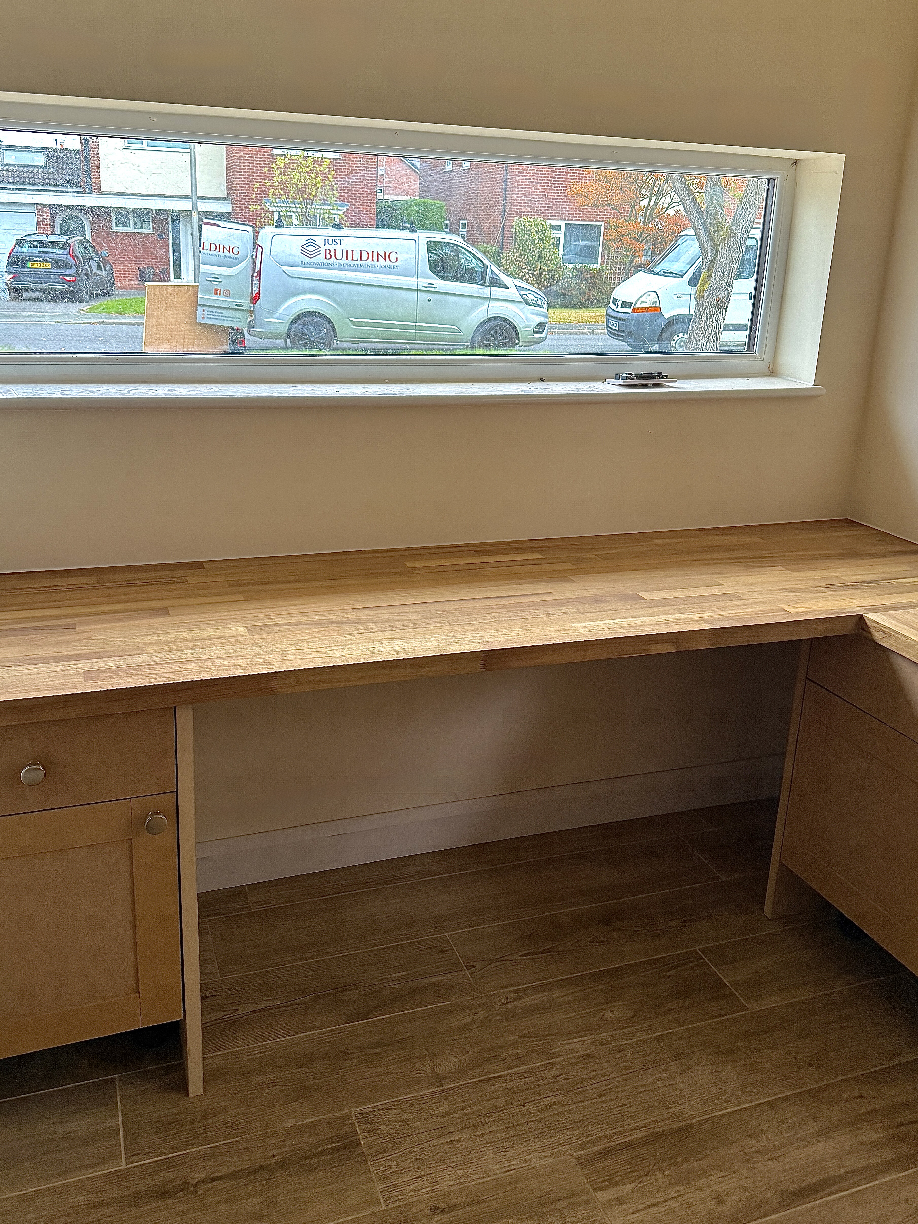 Built-in oak worktop desk with drawer storage below a window